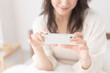 © lielos - ベッドでスマホを見ている女性