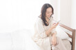 © lielos - 寝室で携帯電話の画面を見ている女性