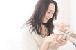 © lielos - 寝室で携帯電話を操作している女性