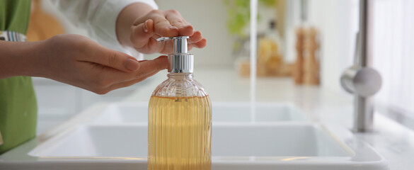 Wall Mural - Woman applying liquid soap on hand indoors, closeup. Banner design