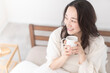 © lielos - 朝、温かい飲み物を飲む女性