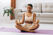 © anatoliycherkas - Young black woman meditating at home, yoga online concept, free space