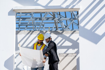 Architects discuss with head engineer about construction project on workplace at construction site.