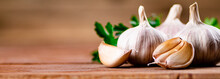 Cloves Of Fresh Garlic With Parsley. On A Wooden Background. High Quality Photo