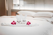 Hotel bed with towel art design shaped as a bear in a flower basket with orchids