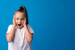 Shocked little girl looking with amazement on blue background