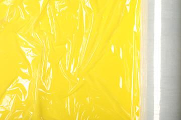 Wall Mural - Roll of plastic stretch wrap film on yellow background, top view