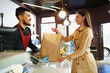 © fotofabrika - Shop assistant handling shopping bag to female customer in grocery store