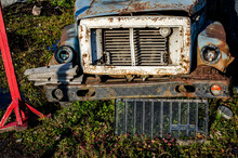 Front View Of The Hood Grille And Bumper Of A Rusty Blue Truck On A Parking Lot Of Broken Machinery