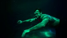 Handsome Brawny Man Is Swimming Inside Pool, Floating Along Bottom, Holding Breath