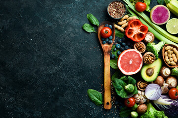 Big set of organic food. On a black chalkboard. Fresh raw fruits, vegetables, nuts, mushrooms and berries. On a black stone background. Top view. Copy space.