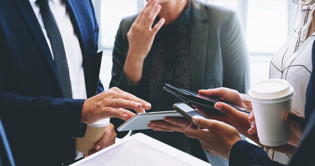 Canvas Print - Technology helps our business move faster. Cropped shot of an unrecognizable group of businesspeople standing and using technology while in the office.