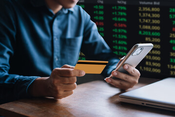 Wall Mural - Businessmen trading stocks online. Stock brokers looking at graphs, indexes and numbers on smartphone and laptop. Business success concept.