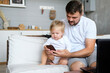 © Oksana - Father's Day. Dad is playing with a small child. Father and daughter sitting on the couch and looking at the phone. High quality photo