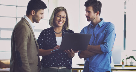 She trusts their advice. Cropped shot of a group of young designers working on a laptop in their office.