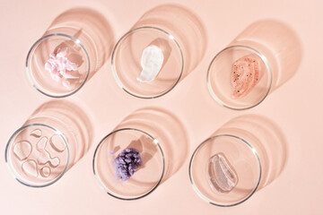 Wall Mural - Cosmetic products, scrub, face serum and gel in many petri dishes on a pastel beige background. Cosmetics laboratory research concept.