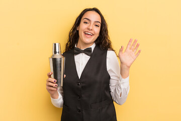 Wall Mural - young pretty hispanic woman smiling happily, waving hand, welcoming and greeting you. bartender and cocktail concept