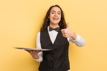 Canvas Print - young pretty hispanic woman feeling cross,showing thumbs down. waiter and tray concept