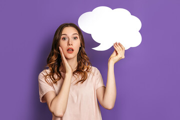 young shocked female student holding blank speech bubble paper isolated on purple background. White paper cloud for text on lilac. Copy space