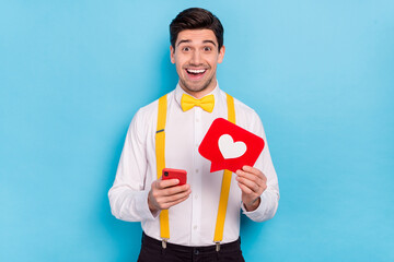 Sticker - Portrait of amazed funny handsome guy hold paper like card gadget isolated on blue color background