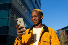 Cheerful Black Man Browsing Smartphone On Sunny Street