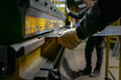 © Nicols - Workers handling piece of metal sheet into a folding machine