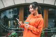 © BullRun - Cheerful woman with takeaway coffee and smartphone