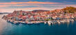 Fantastic sunset in Poros town. Picturesque summer seascape of Myrtoan Sea with a lots of yachts. Attractive evening scene of Peloponnese peninsula, Greece. Traveling concept background..