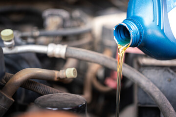 Pouring synthetic lube oil from the canister for car engine oil replacement, machine service and maintenance working photo. Close-up and selective focus.