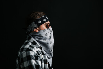 Wall Mural - Fashionable young man with bandana covering his face on black background, space for text