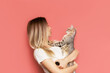 © Марина Демешко - A young caucasian pretty cute blonde woman holds a tabby cat in her hands admiring it isolated on a bright color pink background. The girl babying with a kitten. Fiendship of pet and owner. Banner