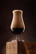 Glass of beer on a wooden box against dark rusty background. Detail of dark beer with overflowing foam head. Shallow depth of field