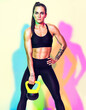 © Romario Ien - Strong woman resting after workout with kettlebell. Photo of athletic woman in black sportswear on white background with effect of rgb colors shadows. Sports motivation and healthy lifestyle