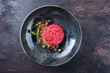 Modern style gourmet tartar raw from beef filet with capers and amarena cherry served with truffle cream and lettuce as top view in a Nordic design plate with copy space