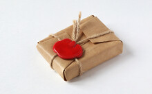 Mail Parcel Wrapped In Craft Paper And Sealed With A Red Wax Seal On A White Background. Packet With Wax Seal, Gift Box With Wax Seal