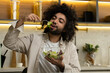© Grustock - Egyptian man with dark kinky hair enjoys eating salad with lettuce from transparent bowl at table in kitchen with stylish furniture