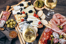 Food Antipasto Prosciutto Ham, Salami, Olives And Grissini Bread Sticks. Cheese On A Board Parmesan, Pecorino, Gorgonzola. Charcuterie Board. Two Glasses Of White Wine Or Prosecco