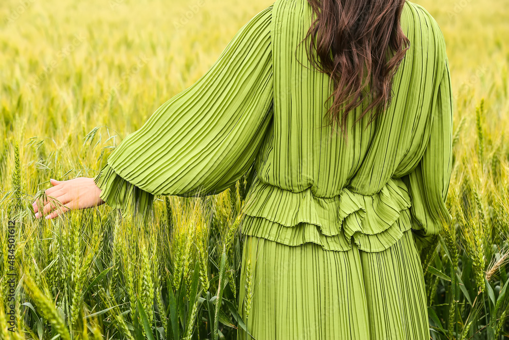 Woman in green wheat field on sunny day