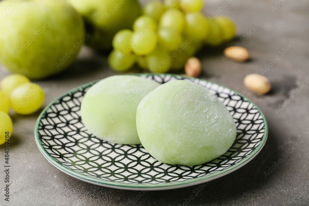Plate with delicious mochi, fruits and nuts on grunge background