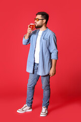 Wall Mural - Handsome man in sunglasses drinking beer on red background