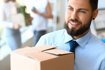 Wall Mural - Handsome man holding box with things in office on moving day, closeup