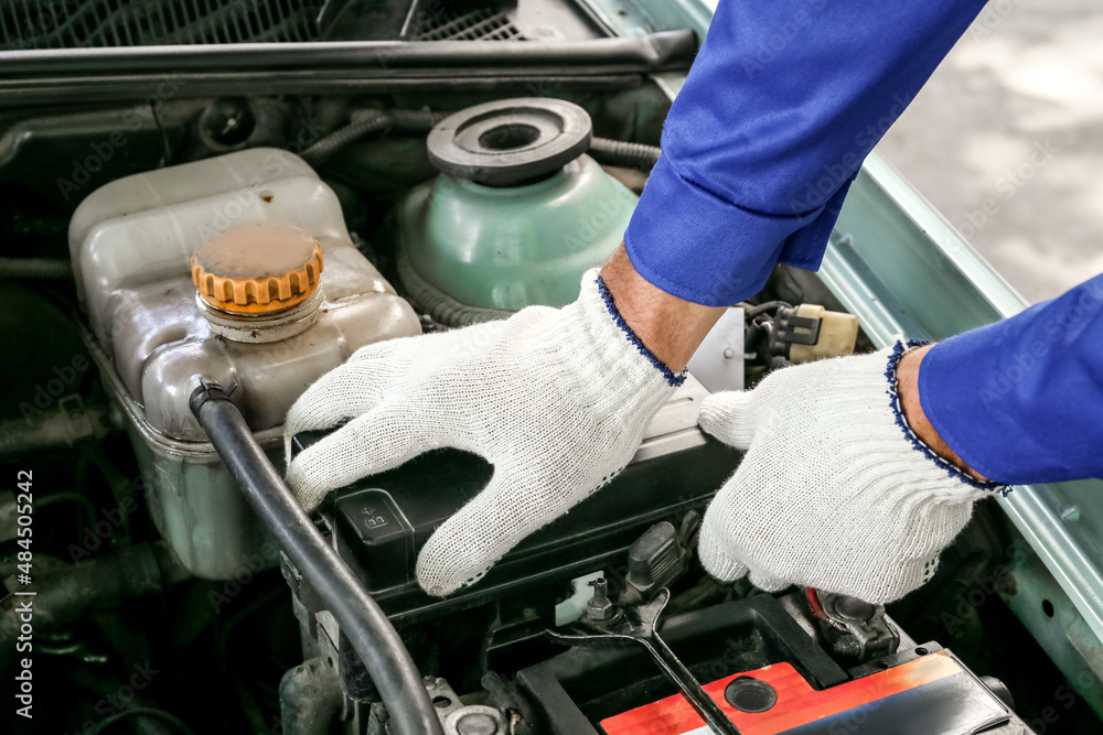 Male mechanic fixing car battery