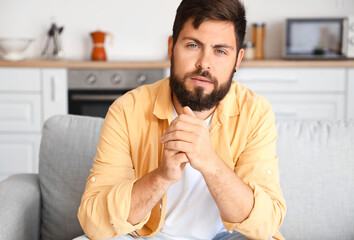 Canvas Print - Handsome man sitting on sofa in kitchen