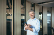 © Liubomir - Successful man uses mobile app on phone for dating, experienced and gray-haired businessman in office
