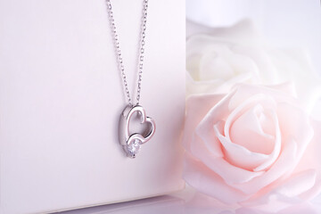 Wall Mural - Diamond heart necklace hanging on white jewelry box soft roses in background