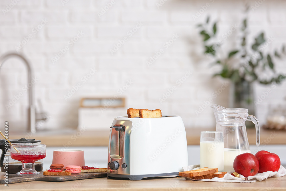 White toaster with tasty food and drink on table in modern kitchen