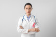 © Pixel-Shot - Female oncologist with pink ribbon on light background. Breast cancer awareness concept