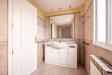 Bathroom With White Wooden Cabinet With Veined Marble Top, Square Mirror Embedded In The Wall And Cream Pink Tiles