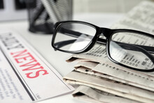 Stack Of Newspapers And Glasses On White Table, Closeup