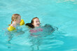 © MNStudio - Cute young girls having fun in outdoor pool. Children learning to swim. Kids having fun with water toys. Family fun in a pool. Summer activities for family with kids.